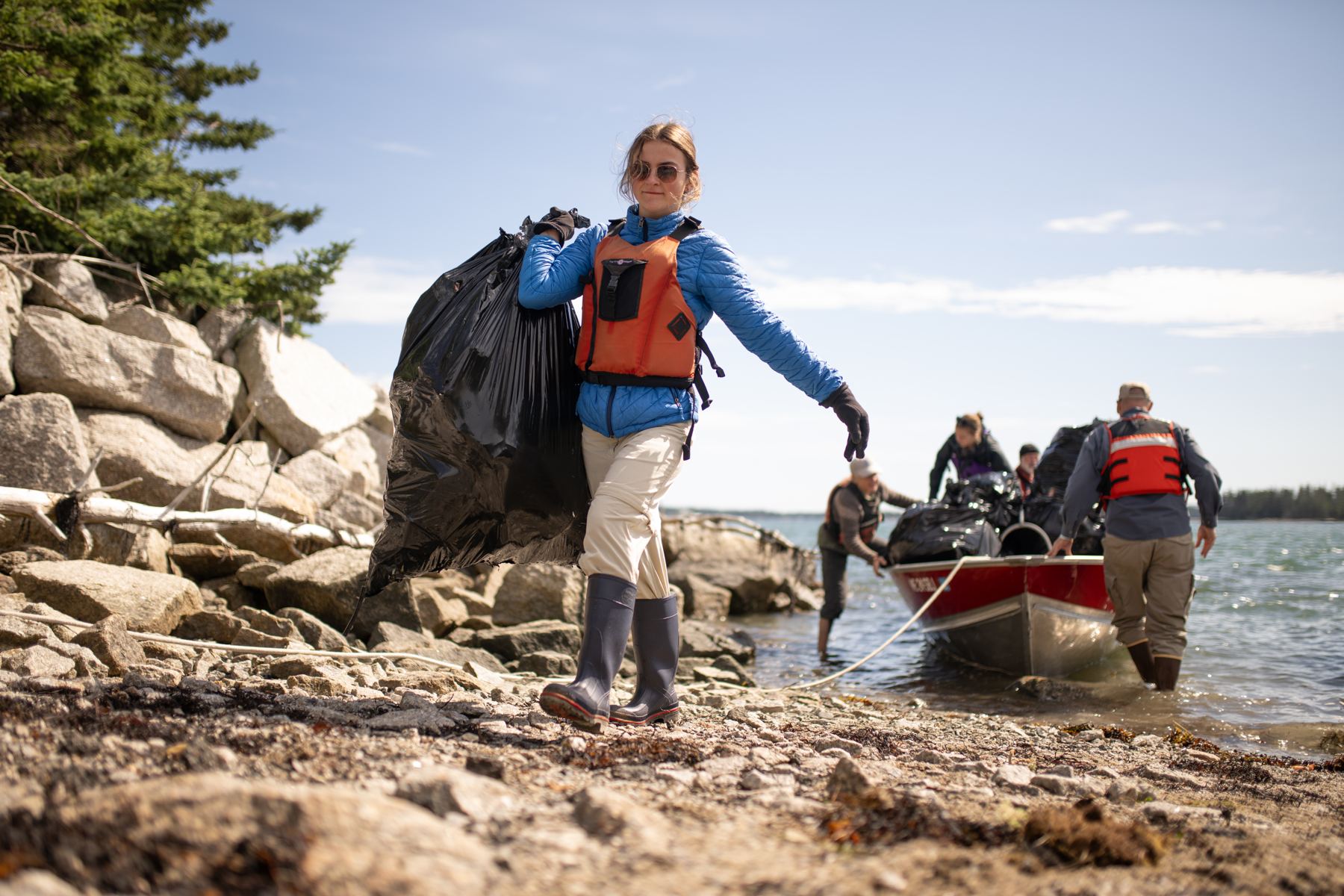 A volunteer hauling debris bags to a boat during an island cleanup